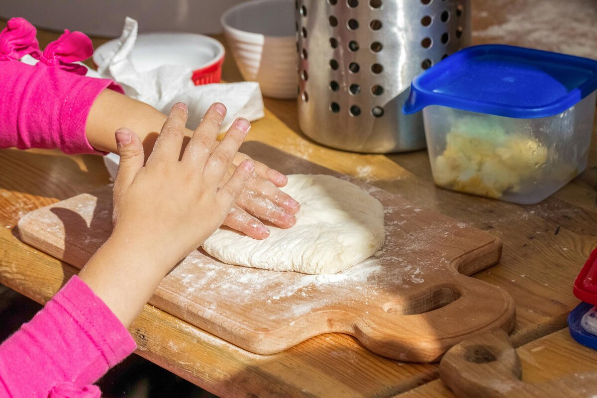 Children's hands kneading bread dough on a floured board during a hands-on history lesson